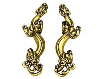 May include: Two antique brass-colored door handles with a dragon design. The handles are curved with a detailed dragon head at the top and ornate scrollwork. The handles are symmetrical and set against a white background.