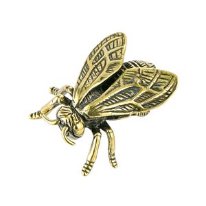 May include: A detailed brass-colored bee figurine with intricate wing and body details. The bee is posed as if in flight, with its wings slightly spread. The sculpture is made of metal and has a vintage or antique appearance.