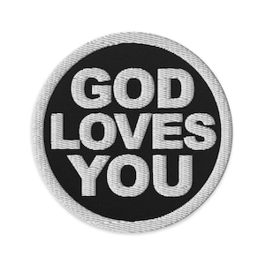 Puede incluir: Parche bordado circular con el texto blanco "GOD LOVES YOU" sobre un fondo negro. El parche tiene un borde blanco cosido. El diseño es simple y audaz.