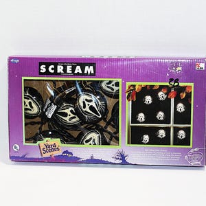 May include: A rectangular purple cardboard box containing a set of string lights with black plastic covers shaped like the Ghostface mask from the movie Scream. The packaging features the movie title, the Yard Scenes logo, and product imagery.