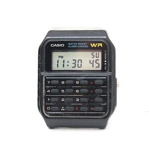 May include: A black Casio digital watch with a calculator keypad. The watch face displays the time as 11:30 PM and the date as SU 45. The watch has the text "WATER RESIST" and "ALARM CHRONO" printed on the face.