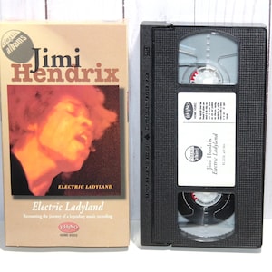 May include: A VHS tape of Jimi Hendrix's Electric Ladyland album. The tape is black with a white label that says "classic albums" and features a photo of Jimi Hendrix. The tape is in a plastic case with a black and white label that says "Jimi Hendrix Electric Ladyland".