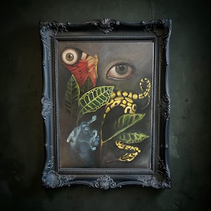 Puede incluir: Una pintura al óleo en un marco negro ornamentado. La obra presenta una composición surrealista con un ojo grande, una mariposa y una criatura serpentina amarilla y negra entre follaje verde. El fondo es oscuro.