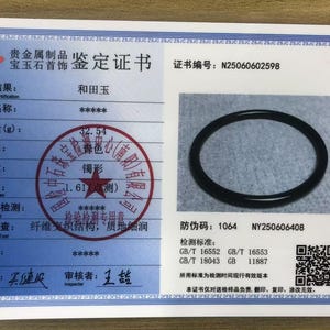 May include: A white rectangular gemstone identification certificate featuring a blue border, a photograph of a black circular bangle, Chinese text, a red circular stamp, a QR code, and the certificate number N25060602598 printed in black ink.