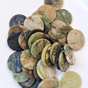 May include: A collection of numerous circular stone discs featuring a variety of natural patterns and colors, including shades of sage green, olive, tan, cream, and charcoal gray. Each disc displays unique veining and smooth, polished surfaces.