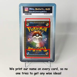 Op de afbeelding: Een gegradeerde Pok&eacute;mon-verzamelkaart in een doorzichtige plastic houder met een blauwe rand. De achterkant van de kaart toont het Pok&eacute;mon-logo en een centrale bol. Het label bevat de tekst Shiny_Hunter's_Guild en www.shinyhuntersguild.store.