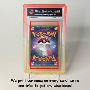 May include: A graded Pok&eacute;mon trading card encased in a clear plastic slab with a pink and yellow gradient border. The card features the classic blue back design with a central Pok&eacute; Ball and the text Shiny_Hunter's_Guild printed on the card surface.