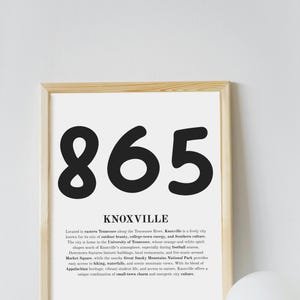Peut inclure: Impression encadrée avec le chiffre "865" en noir, au-dessus de "KNOXVILLE". Le texte décrit Knoxville, Tennessee, dans un style moderne. Le cadre est de couleur bois clair. L'impression est de forme rectangulaire.