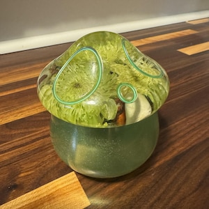 Recipiente de resina hecho a mano con forma de hongo: crisantemos verdes, anillos turquesa y base con purpurina.