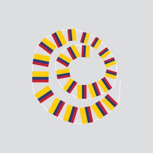 Op de afbeelding: Een spiraalvormig ontwerp van kleine Colombiaanse vlaggen, met gele, blauwe en rode strepen. De vlaggen zijn gerangschikt in een cirkelvormig patroon tegen een lichtgrijze achtergrond, wat een feestelijke uitstraling creëert.
