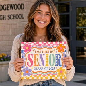 以下が含まれることがあります： LAST FIRST DAY SENIOR CLASS OF 2027という文字がカラフルで太いフォントで書かれた長方形のサイン。ピンクと白のチェック柄の縁取り、波線、そしてピンク、オレンジ、紫、黄色の4つの大きな花がデザインされています。