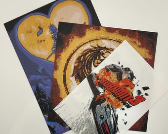 May include: A collection of square art prints featuring fantasy-themed illustrations. One print shows a heart-shaped moon with a figure holding a key-shaped weapon. Another print displays a circular design with a dragon. The third print has the word "BURNOUT" in red.