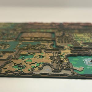 May include: A detailed, three-dimensional map with a layered design. The map features a combination of green, brown, and black colors, with intricate details suggesting terrain and structures. The overall aesthetic is reminiscent of a topographical representation.