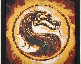 May include: Square framed artwork featuring a detailed dragon design within a gold circle. The dragon is brown and gold, set against a background of red and gold hues. The artwork is framed in a black square.
