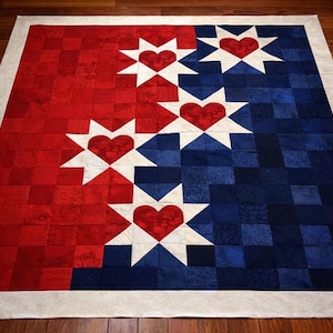 May include: A handmade quilt with a patriotic theme. The quilt features a red and blue color scheme, divided into two sections. White starbursts with red heart centers are arranged across the quilt. The quilt is bordered with a neutral-colored fabric.