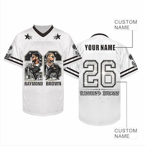 May include: A white football jersey featuring black V-neck trim, two stars on the chest, and the number 26 with portraits of two men. The back displays the text YOUR NAME, the number 26, and the name RAYMOND BROWN with custom name placeholders.