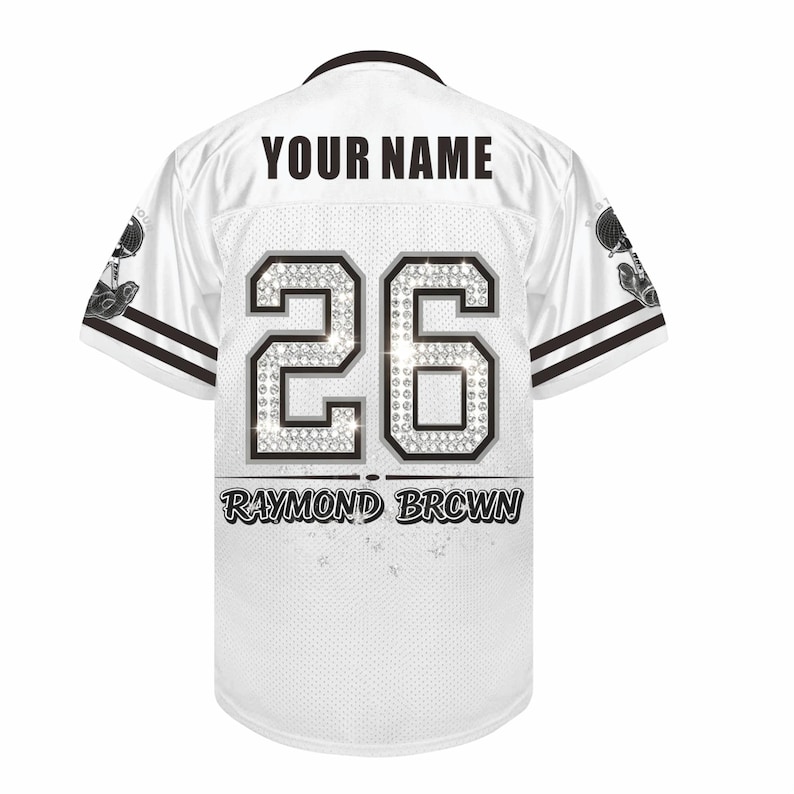 May include: A white sports jersey featuring the text YOUR NAME at the top, the number 26 with a diamond-like pattern in the center, and the name RAYMOND BROWN printed below. The sleeves have black stripes and a graphic of a trophy on each side.