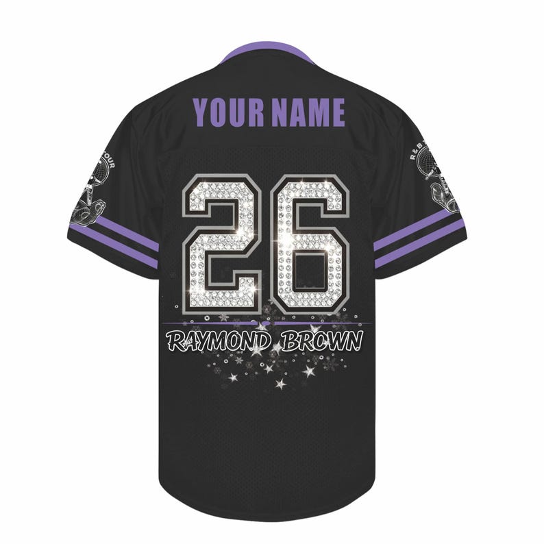 May include: A black baseball jersey with purple trim on the collar and sleeves. The back features the text YOUR NAME, the number 26 in a silver diamond-like pattern, and the name RAYMOND BROWN with a graphic of white stars and sparkles.