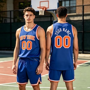 Op de afbeelding: Een blauwe basketbalshirt en short set met oranje en witte biezen. De voorkant bevat de tekst NEW YORK en het nummer 00 in oranje met witte omlijning. De achterkant toont de tekst YOUR NAME en het nummer 00 in het wit.