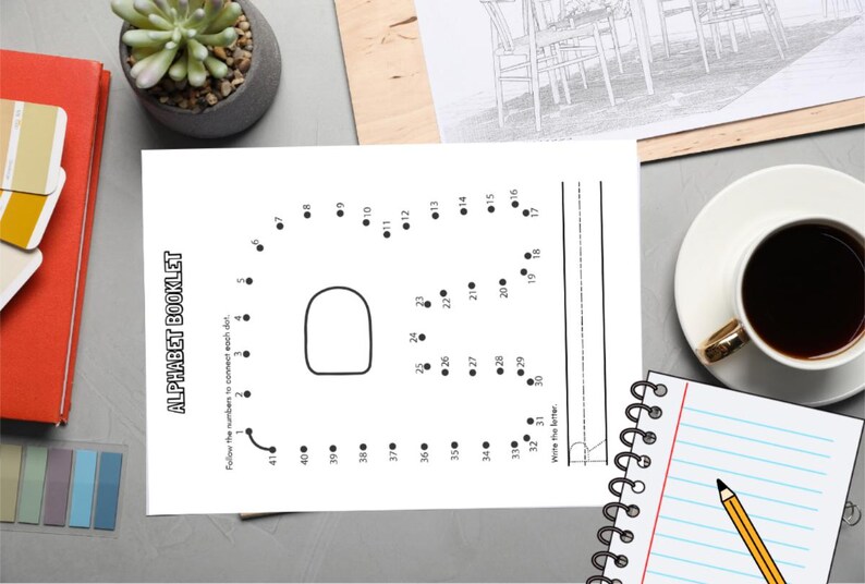 May include: A black and white alphabet booklet with the text "ALPHABET BOOKLET" and a dot-to-dot letter. A cup of coffee, a notepad with a pencil, and a succulent plant are also visible.