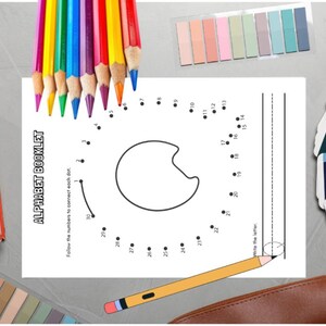 May include: An assortment of school supplies including colored pencils, sticky notes, a notebook, and a dot-to-dot worksheet. The worksheet is labeled "ALPHABET BOOKLET" and features a letter outline. A pencil case and color swatches are also present.