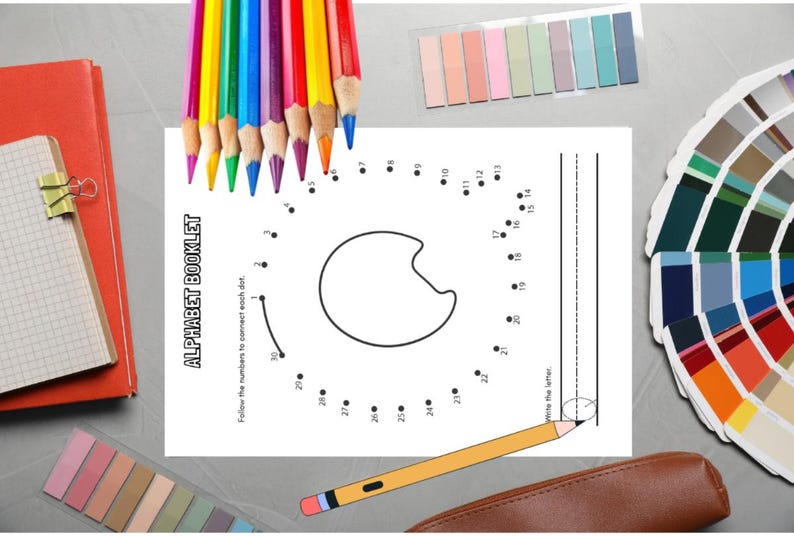 May include: An assortment of school supplies including colored pencils, sticky notes, a notebook, and a dot-to-dot worksheet. The worksheet is labeled "ALPHABET BOOKLET" and features a letter outline. A pencil case and color swatches are also present.
