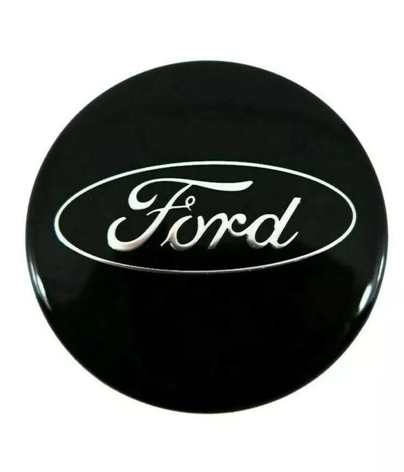 May include: A black, circular Ford emblem with a glossy finish. The word "Ford" is written in a stylized, silver font within a white oval. The emblem is likely for a car.