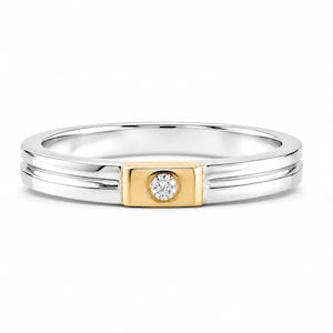 May include: A two-tone ring featuring a polished silver band with a central horizontal groove. A rectangular gold-toned inlay is set into the front of the band, featuring a single round brilliant-cut white diamond set in a flush bezel setting.
