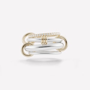May include: A multi-band ring featuring a combination of gold and silver tones. The ring has a series of interlocking bands, with a top band adorned with small, sparkling stones. The design is modern and elegant.
