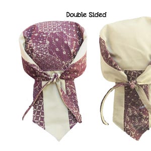 May include: Double-sided head wrap with a cream-colored interior and a patterned exterior in shades of burgundy and cream. The wrap is tied in a knot at the front and features the text "Double Sided".