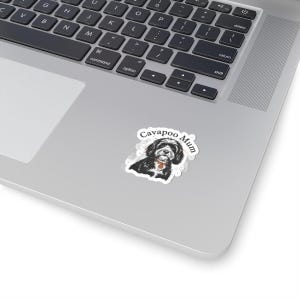 May include: A sticker featuring a black and white Cavapoo dog illustration with the text "Cavapoo Mum". The sticker is on a laptop.