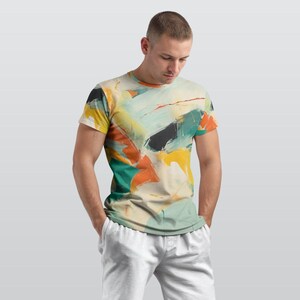 May include: A short-sleeved t-shirt with an abstract art design. The shirt features a colourful pattern with yellow, orange, teal, and black brushstrokes. The shirt is a neutral colour and is paired with white sweatpants.