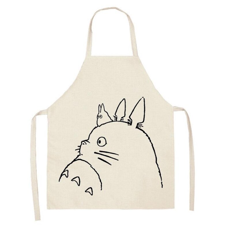 Puede incluir: Delantal beige con un dibujo lineal negro de un personaje de Totoro. El delantal tiene un lazo para el cuello y lazos en la cintura. El dise&ntilde;o de Totoro incluye la cara del personaje y una criatura m&aacute;s peque&ntilde;a en su cabeza. Un divertido accesorio de cocina.
