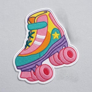 May include: Embroidered patch of a colorful roller skate. The design features a teal, pink, yellow, orange, and purple skate with pink wheels and a yellow star. The patch has a white border.