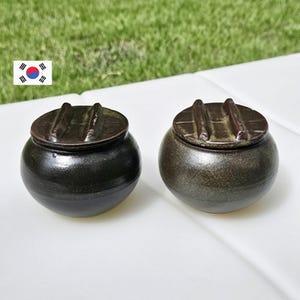 May include: A set of three ceramic mugs with a speckled, matte finish. The mugs are in shades of cream, light gray, and dark gray. Each mug has a simple, minimalist design and a rounded handle. Perfect for coffee or tea.