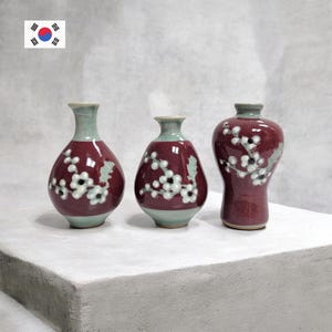 May include: A set of three ceramic mugs with a speckled, matte finish. The mugs are in shades of cream, light gray, and dark gray. Each mug has a simple, minimalist design, perfect for coffee or tea.