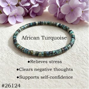 May include: A circular bracelet made of small, flat, disc-shaped African Turquoise beads with mottled green, blue, and black patterns. Text reads: African Turquoise, Relieves stress, Clears negative thoughts, Supports self-confidence, #26124.