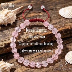 May include: A bracelet made of faceted light pink rose quartz beads with a red cord featuring an adjustable sliding knot closure and two small white beads at the ends. The text #26084, Rose Quartz, Attract love, Support emotional healing, and Calms stress and anxiety is visible.