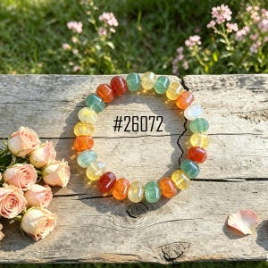 Puede incluir: Una pulsera de cuentas multicolores con cuentas redondeadas en rojo, naranja, amarillo, verde y blanco. La pulsera se muestra sobre una superficie de madera envejecida, con el texto "#26072" en el centro.