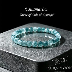 May include: Aquamarine beaded bracelet. The bracelet features faceted, light blue-green aquamarine beads. The text "Aquamarine" and "Stone of Calm & Courage" is displayed above the bracelet. The Aura Moon logo is in the bottom right corner.