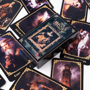 May include: A deck of The Baroque Tarot cards, Second Edition, with ornate gold detailing. The box features a framed image and the deck includes cards with classical art illustrations. The cards are scattered on a white surface.