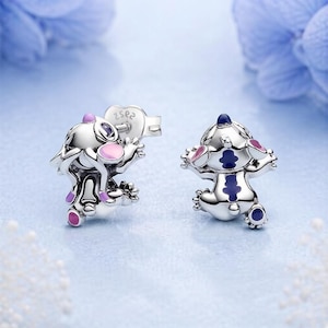 Peut inclure: Une paire de boucles d'oreilles &agrave; clous en argent en forme de cr&eacute;ature de dessin anim&eacute; avec des accents en &eacute;mail. Une boucle pr&eacute;sente des d&eacute;tails roses et violets, tandis que l'autre affiche des motifs bleu fonc&eacute; et violets. Finition m&eacute;tallique.