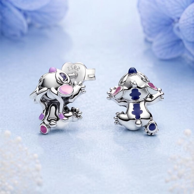 Peut inclure: Une paire de boucles d'oreilles &agrave; clous en argent en forme de cr&eacute;ature de dessin anim&eacute; avec des accents en &eacute;mail. Une boucle pr&eacute;sente des d&eacute;tails roses et violets, tandis que l'autre affiche des motifs bleu fonc&eacute; et violets. Finition m&eacute;tallique.