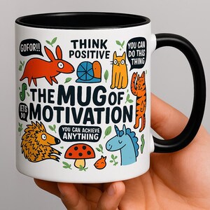 Può includere: Una tazza di ceramica bianca con interno e manico neri. La tazza è decorata con animali dei cartoni animati colorati e la scritta "The Mug of Motivation". Il testo aggiuntivo include "Think Positive" e "You Can Achieve Anything".