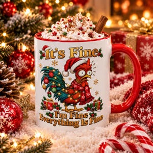 Peut inclure: Un mug en céramique blanc avec une anse et un bord rouges, rempli de crème fouettée et d'un bâton de cannelle. Le mug présente un coq paniqué portant un bonnet de Père Noël et une écharpe, avec le texte "It's Fine" et "I'm Fine Everything Is Fine."
