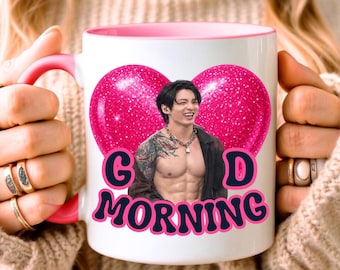 May include: A white ceramic mug with a pink handle and interior, featuring a large glittery pink heart graphic. Inside the heart is a photograph of a person with dark hair, tattoos, and a necklace. The text GOOD MORNING is printed in black.