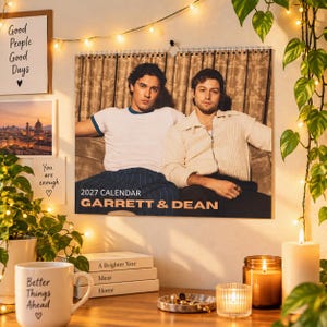 May include: A 2027 wall calendar featuring a photograph of two men sitting together. The text on the calendar reads 2027 CALENDAR GARRETT & DEAN. One person wears a white t-shirt and the other wears a cream-colored long-sleeve shirt.