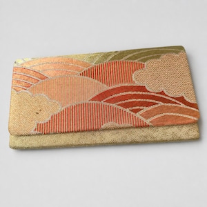 May include: A rectangular clutch bag featuring a woven fabric flap with a pattern of orange, red, and gold curved lines and cloud shapes. The lower portion of the clutch is a solid, textured gold fabric with a subtle, repeating geometric pattern.
