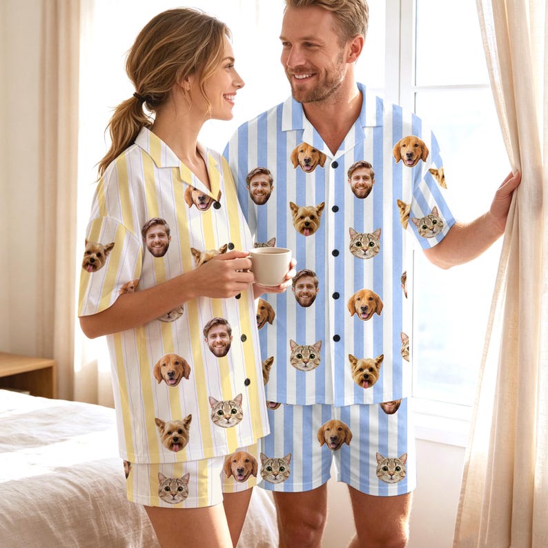 May include: A set of matching pajamas featuring a repeating pattern of various dog and cat faces. The left set has yellow and white vertical stripes, while the right set has light blue and white vertical stripes, both with button-down shirts.