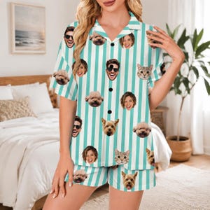 May include: A short-sleeved button-down pajama shirt and matching shorts set featuring a vertical teal and white striped pattern. The fabric is decorated with a repeating print of various human faces and pet dog and cat faces throughout.